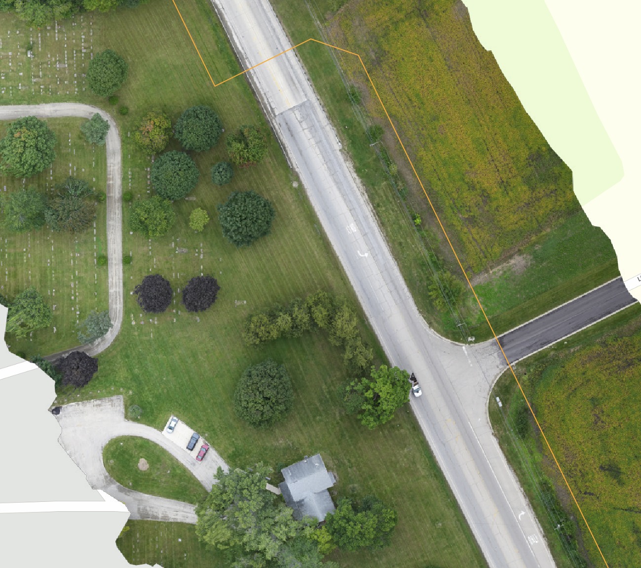 Full-resolution drone orthomosaic of a road intersection showing pavement markings, curbs, and parked vehicles